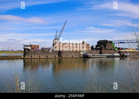 Krefeld (Ürdingen) - März 1. 2021: Blick auf alten Binnenladerhafen am Rhein mit Kran, Wasserschiff und Fabrikgebäude gegen Blue sk Stockfoto