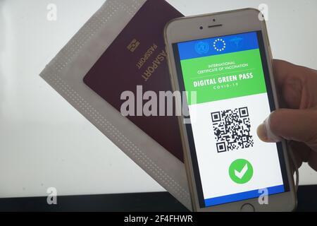 Der digitale grüne Pass der europäischen Union mit dem QR-Code auf dem Bildschirm eines Mobiltelefons, das von einer Hand am Flughafen für die Reise gehalten wird. Immunitätspass, Stockfoto