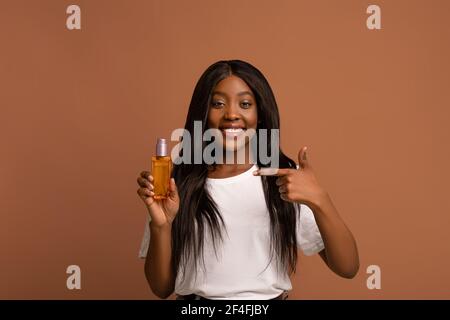 Hübsche schwarze Frau mit langen schönen Haaren zeigt Haar Produkt Stockfoto