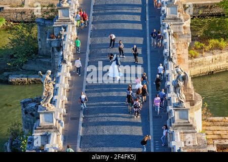 Gruppe von Menschen, Braut und Bräutigam jungen Paar Fotosession auf Ponte Sant Angelo Brücke in der Stadt Rom in Italien, Luftaufnahme Stockfoto