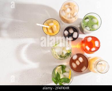 Verschiedene erfrischende alkoholfreie Getränke in Gläsern mit Eis. Verschiedene Säfte, hausgemachte Limonade, Eiskaffee, Eistee und Smoothies auf White BA Stockfoto