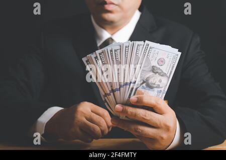 Businessman Hand Holding Money - US-Dollar. Investition, Erfolg und profitable Geschäftskonzepte Stockfoto