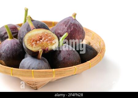 Frische lila Feigenfrucht und Scheiben in Bambuskorb isoliert auf weißem Hintergrund, Figuren sind reich an Kalzium und enthält Antioxidantien Es hilft zu verhindern Stockfoto