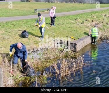 Glasgow, Schottland, Großbritannien. März 2021, 21st. Wetter in Großbritannien: An einem sonnigen Tag kehrte der Frühling in die Stadt zurück, als viele Menschen auf dem Schleppweg des Forth und clyde Kanals spazierten und Rad fuhren und vorcovid Szenen sahen. Als Freiwillige Kanalarbeiter säubern den Müll und entfernen die Oblekte aus den Wasserstraßen im Hintergrund. Quelle: Gerard Ferry/Alamy Live News Stockfoto