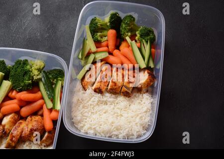 Gesunde ausgewogene Lunchboxen. Gegrilltes Hähnchen, Karotten, Gurken, Brokkoli und weißer Reis. Lunchboxen mit Lebensmitteln bereit für die Arbeit oder die Schule zu gehen. Aus Stockfoto