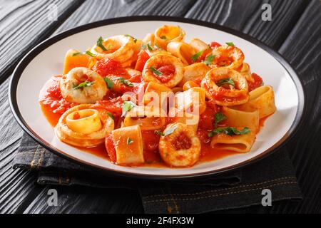 Authentische italienische Calamarata Pasta mit Tintenfisch und Tomate close-up in einem Teller auf dem Tisch. Horizontal Stockfoto
