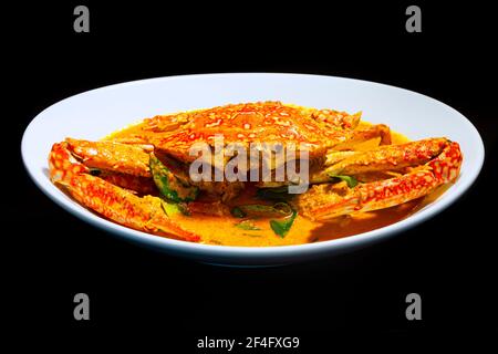 Blaues Krabbencurry in Thai-infundierten roten Kokosnuss-Curry-Sauce auf dunklem launischem Hintergrund, selektiver Fokus. Stockfoto