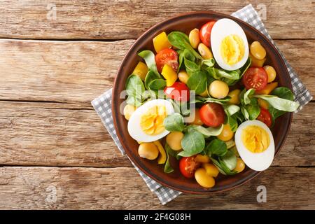 Frühstück mit gekochten Eiern und Salat aus Lupine Bohnen, Tomaten und gemeinsamen Cornsalat Nahaufnahme in einem Teller auf dem Tisch. Horizontale Ansicht von oben Stockfoto