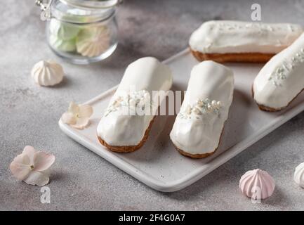 Weiße Glasur Eclare auf weißem Servierbrett Stockfoto