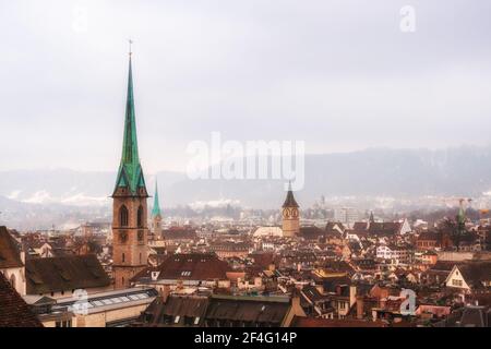 Blick auf Zürich an einem nebligen Wintertag. Gotische Kirchtürmen im Hintergrund des Alpenrückens Stockfoto