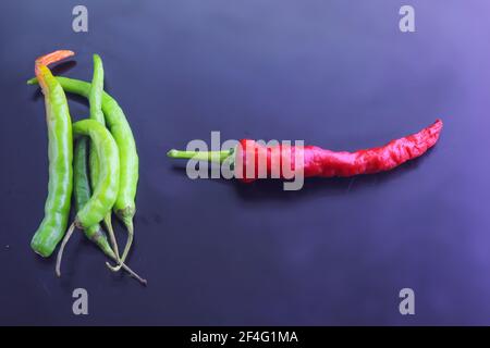 Ein Haufen grüner Chilischoten und ein roter Auf dem dunklen Hintergrund angeordnet Stockfoto