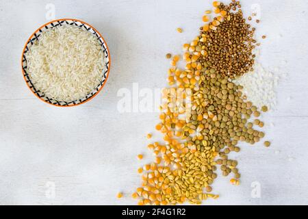 Eine Nahaufnahme einer Schüssel mit weißem Reis und Verschiedene Körner isoliert auf einer weißen Oberfläche Stockfoto