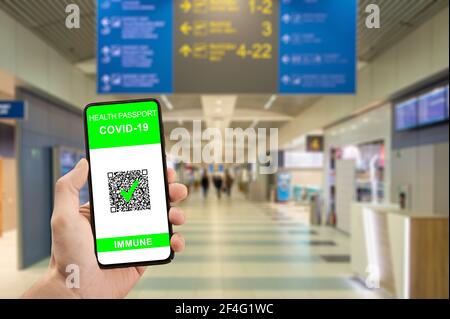 Reisende Hand halten Telefon mit Gesundheit Pass der Impfung Zertifizierung. Gesundheitsausweis am Telefon am Flughafen wurden von Coronavirus geimpft. Stockfoto