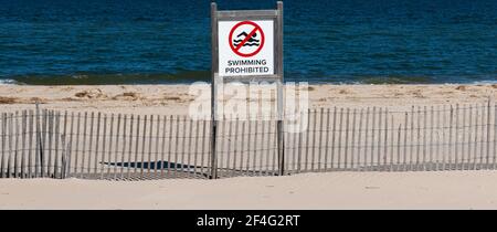 Schwimmen am Strand im Sunken Meadow State Park an einem sonnigen Märztag mit einem Zaun vor dem Strand verboten. Stockfoto