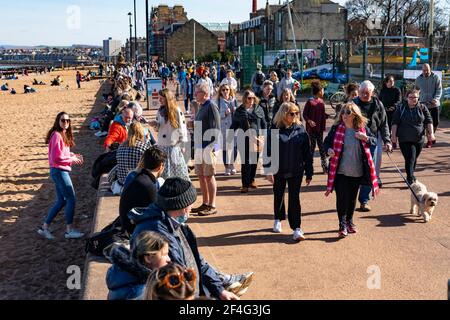 Portobello, Schottland, Großbritannien. 21. März 2021. Warme Temperaturen, blauer Himmel und Sonnenschein brachten die Massen an diesem Nachmittag zum beliebten Portobello Strand und zur Promenade. Trotz der andauernden covid-19 Lockdown wurde die Küste mit Mitgliedern der Öffentlichkeit gedrängt. Viele Cafés waren offen und boten Essen zum Mitnehmen an. Iain Masterton/Alamy Live News Stockfoto