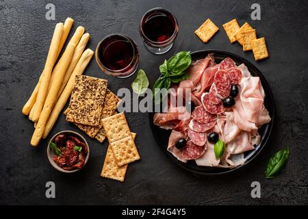 Vorspeisen mit verschiedenen Antipasti, Wurstwaren, Snacks und Rotwein. Wurst, Schinken, Tapas, Oliven und Cracker für Buffet-Party. Draufsicht, flach liegend Stockfoto