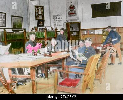 Uniformierte westliche Militärangehörige und ein Chinese in Straßenkleidung lesen an einem Tisch, während Kollegen im Hintergrund Billard spielen, in einem Armeestaurant, Peking, China, 1918. Aus der Sammlung Sidney D. Gamble Photographs. () Stockfoto