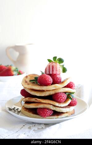 Leckere Pfannkuchen mit frischen Himbeeren und Honig auf dem Tisch. Weißer Hintergrund. Stockfoto