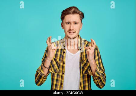 Fokussierter Mann mit gekreuzten Fingern, blauer Hintergrund Stockfoto