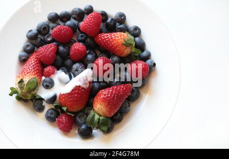 Frisches Obst. Frische Himbeeren, Heidelbeeren und Erdbeeren auf einem weißen Teller. Direkt darüber. Stockfoto