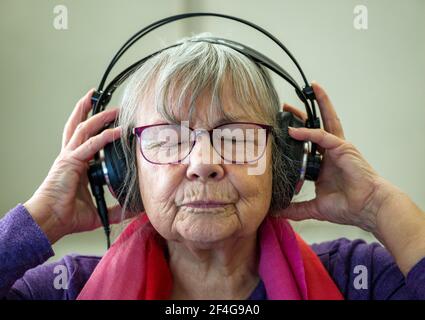 17. März 2021, Brandenburg, Grünheide: Die 77-jährige Dorothea Kiesecker, Mitglied des Vereins Radio Ginseng e.V., sitzt im Sendestudio und hört die Musik mit ihren Kopfhörern. Senioren machen jetzt Radio in Grünheide. Ende März soll ihr Dienst gestartet werden - vorerst ausschließlich im Internet. Brandenburgs erster Seniorenfunk will auch jüngere Zuhörer und Mitstreiter anziehen. Moderatoren werden dringend benötigt. Foto: Patrick Pleul/dpa-Zentralbild/ZB Stockfoto