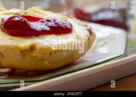 Gebutterter Scone mit Erdbeermarmelade auf einem Beilagenteller Stockfoto