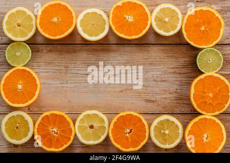 Orangen, Limetten und Zitronen Rutschen auf Holztisch Blick von oben. Wunderschön Hintergrund mit frischem Obst halb geschnitten.gesunde Ernährung Vitamin C.Sommer tropica Stockfoto