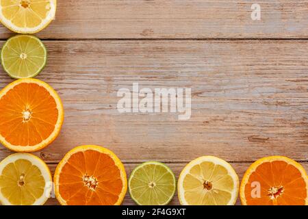 Orangen, Limetten und Zitronen Rutschen auf Holztisch Blick von oben. Wunderschön Hintergrund mit frischem Obst halb geschnitten.gesunde Ernährung Vitamin C.Sommer tropica Stockfoto