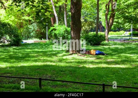 Mann liegt im Stadtpark . Schlafen auf dem grünen Gras . Unbeschwerter Lebensstil Stockfoto