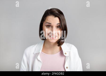 Menschliche Gesichtsausdrücke und Emotionen. Porträt der jungen Brünette Frau in rosa Tank und weißem Hemd Blick auf die Kamera. Stockfoto