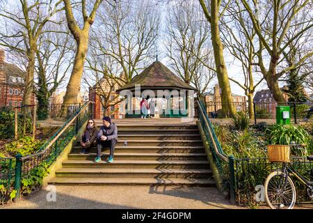 Menschen, die im Arnold Circus im Boundary Estate, Londons erstem council Estate, Shoreditch, London, Großbritannien, sitzen Stockfoto