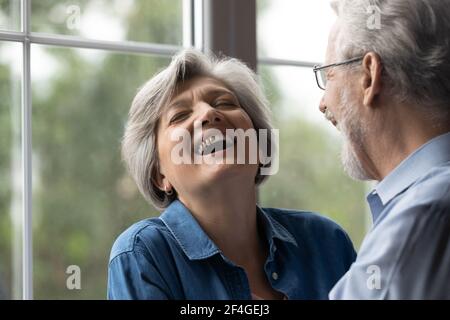 Fröhlicher pensionierter Ehemann lässt geliebte alte Frau vor Lachen weinen Stockfoto