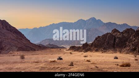 Buggy Ausflug in einer Steinwüste bei Sonnenuntergang. Berglandschaft mit Geländewagen mit Touristen in Sharm el-Sheikh. Stockfoto