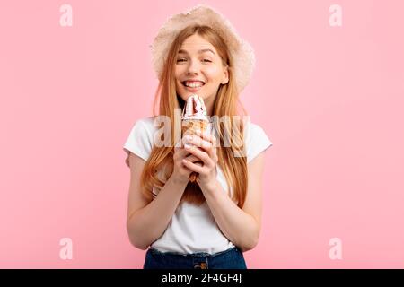 Glückliche junge Frau essen Eis isoliert auf rosa Hintergrund Stockfoto