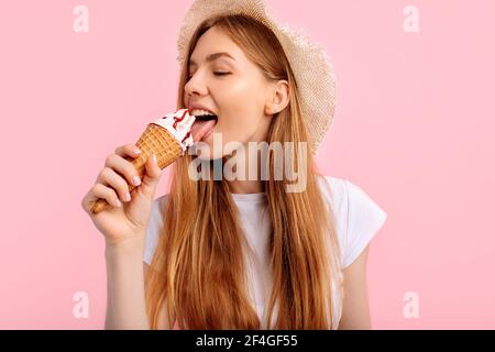 Charmante junge Frau, in einem Sommerhut, mit köstlichen Eis auf einem rosa Hintergrund Stockfoto