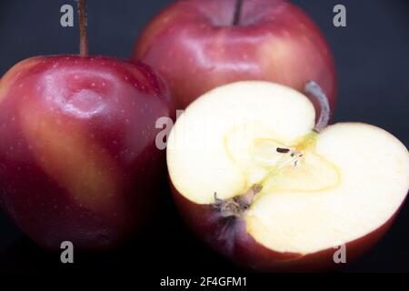 Rote reife Äpfel auf schwarzem Hintergrund.roter Apfel schneiden.ein halber Apfel. Stockfoto