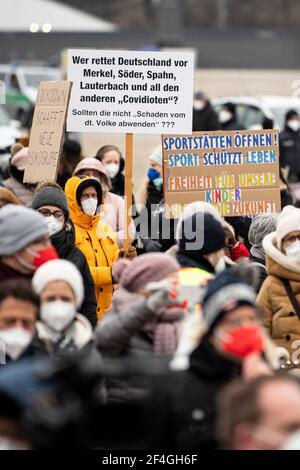 21. März 2021, Bayern, München: Demonstrationsteilnehmer halten bei einer Kundgebung der Organisation 'GemeinsamZukunft' gegen die Sperrung der Theresienwiese-Schilder mit der Aufschrift 'Lockdown schafft neue Risikogruppe', 'Wer rettet Deutschland vor Merkel, Söder, Spahn, Lauterbach und anderen 'Covidioten'? Sollten sie nicht 'Schaden vom deutschen Volk abwenden' ???' Und "Open Sportanlagen! Sport schützt das Leben. Freiheit für unsere Kinder. Sie sind die Zukunft in ihren Händen. Die Teilnehmer der Kundgebung wollen friedlich mit Abstand und FFP2 Masken gegen die Sperre protestieren. Foto: Matthias Bal Stockfoto