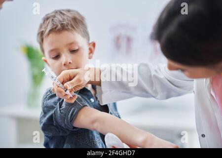 Kleiner Junge wird vom Kinderarzt geimpft Stockfoto