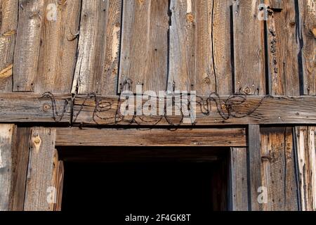 USA, Colorado, Westcliffe, Music Meadows Ranch. Alte hölzerne Scheunenwand mit Stacheldraht BEGRÜSSUNGSSCHILD. Eigenschaft Freigegeben. Stockfoto