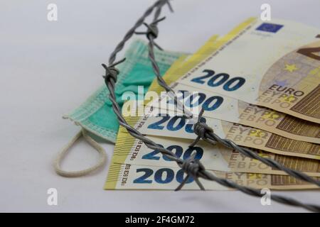 200-Euro-Banknoten, gebrannt mit Stacheldraht und medizinischer Maske, isoliert auf Weiß Stockfoto