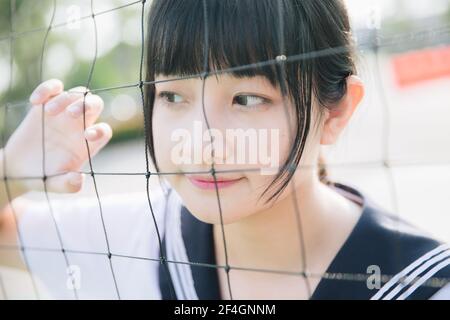 Portrait von schönen asiatischen japanischen High School Mädchen Uniform suchen Mit Netz auf grünem Hintergrund Stockfoto