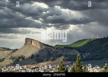Blick auf den Gipfel der Sierra Elvira in Albolote (Granada) Mit einem dramatischen bewölkten Himmel, der durch Strahlen durchlässt So Stockfoto