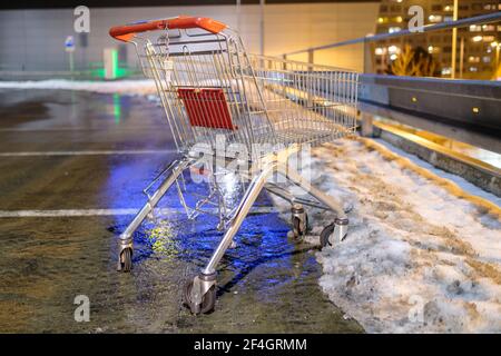Ein verlassener Einkaufswagen, der im Winter auf der Straße in der Nähe des Supermarkts steht. Stockfoto