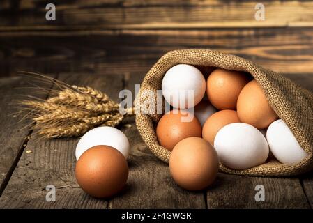 Die Eier im Sack und die Garbe des Weizens auf dem alten Holztisch Stockfoto