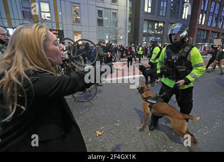 Ein Polizeibeamter mit einem Polizeihund trifft auf Demonstranten vor der Polizeistation Bridewell, als sie an einem Protest "Kill the Bill" in Bristol teilnehmen und gegen das umstrittene Polizei- und Verbrechensgesetz der Regierung demonstrieren. Bilddatum: Sonntag, 21. März 2021. Stockfoto