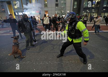 Ein Polizeibeamter mit einem Polizeihund trifft auf Demonstranten vor der Polizeistation Bridewell, als sie an einem Protest "Kill the Bill" in Bristol teilnehmen und gegen das umstrittene Polizei- und Verbrechensgesetz der Regierung demonstrieren. Bilddatum: Sonntag, 21. März 2021. Stockfoto