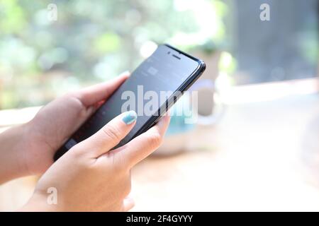 Nahaufnahme auf Frau Hand hält Smartphone Handel Aktien und Daten im Coffee Shop Hintergrund Geschäftskonzept Stockfoto