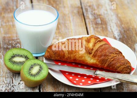 Einfaches kontinentales Frühstück: Französisches Croissant, Kiwi-Obst und ein Glas Milch Stockfoto