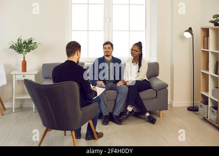 Ein sehr zufriedenes gemischtes Paar, das Familienpsychiater oder Finanzberater trifft Stockfoto