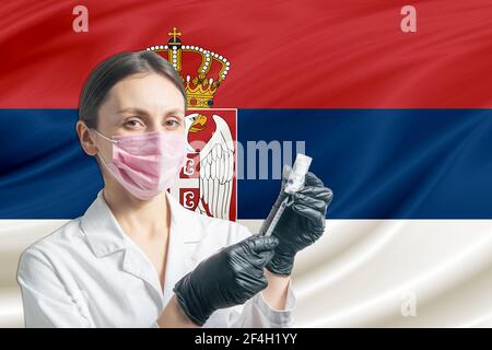 Die Ärztin bereitet die Impfung vor dem Hintergrund der serbischen Flagge vor. Impfkonzept Serbien. Stockfoto